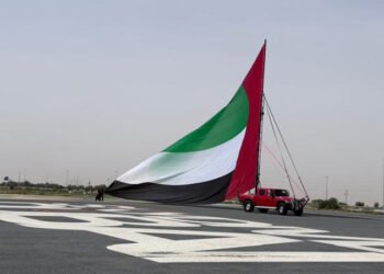 A citizen violates the expectations of artificial intelligence by turning the largest flagpole of the UAE into a Guinness record.