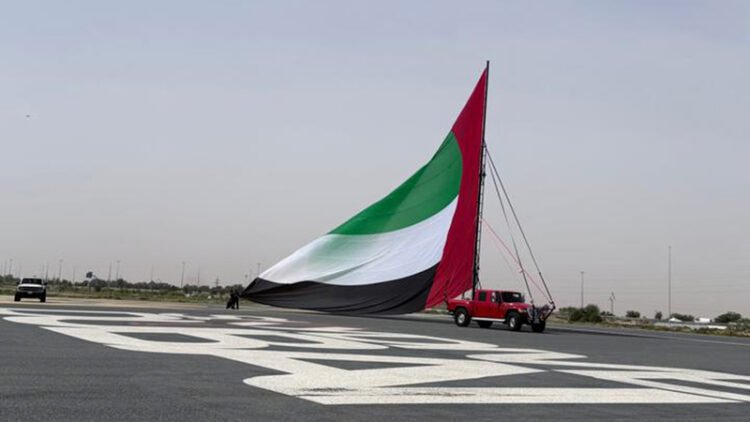 A citizen violates the expectations of artificial intelligence by turning the largest flagpole of the UAE into a Guinness record.