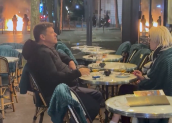 Watch: Blasé French couple smoke and drink while riots rage outside